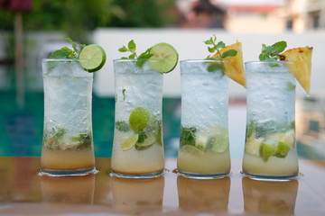 pineapple mojito cocktail and lime mojito cocktail at swim pool background