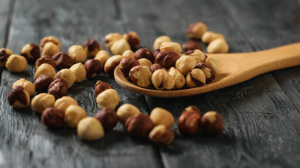 Roasted hazelnuts in a spoon on a black wooden table.