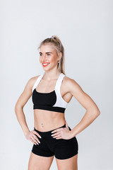 Fototapeta na wymiar Healthy fit strong young woman in sportswear standing on gray.