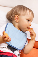 Little baby boy eating biscuit, dessert for kids in preschool or nursery concept