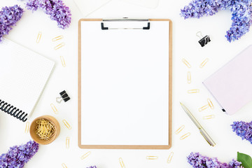 Feminine composition with clipboard, lilac flowers and accessories on white background. Spring time. Flat lay, top view.