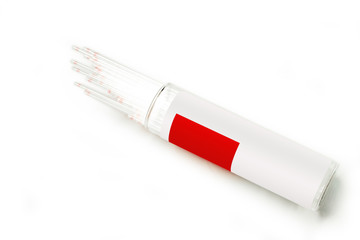 Closeup of medical capillary glass tube emerged from container on white background., Designed for both safe blood collection as well as accurate micro-hematocrit determinations Precision.