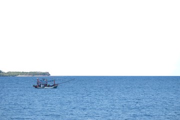 Obraz premium Blurred a fishing boat sailing in deep blue sea on white sky background 