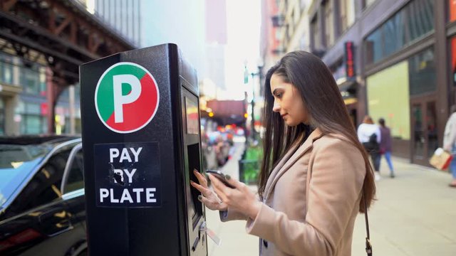 girl paying for parking at the parking meter in chicago Illinois