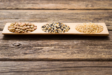 peeled and unpeeled sesame seeds, green lentils, old wooden table