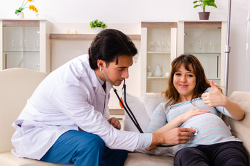 Fototapeta premium Young handsome doctor visiting pregnant woman at home 