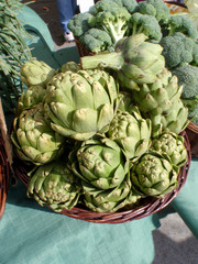 Pile of Artichoke and broccoli in baskets on display