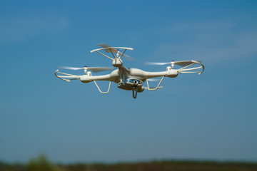 white quadcopter with camera for photo and video shooting flying in the sky