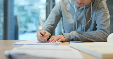 Woman write on the paper note with cellphone at library