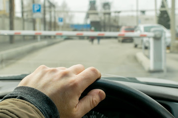 Close up, the hand of the driver of the car on the background of a closed barrier to enter the Parking lot of the protected object