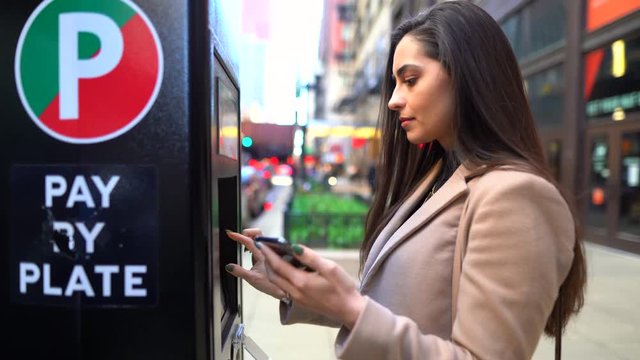 girl paying for parking at the parking meter in chicago Illinois