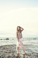 Young woman in beige lace dress outdoor on ocean coast