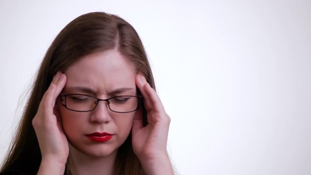Close up view of tired young woman in glasses with headache over white background
