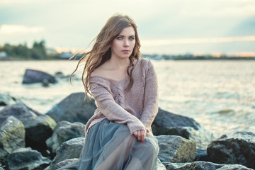 Beautiful woman with brown hair on ocean coast, romantic lifestyle portrait