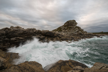 Langzeitbelichtung des dramatischen Himmels mit dunkelblauen Wolken über der felsigen bretonischen Küste, Frankreich, Bretagne, Finistere