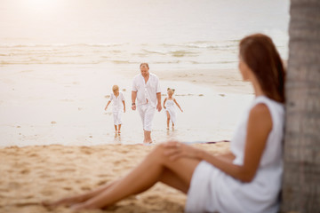 Fototapeta na wymiar Happy young family on the sunset at the beach.