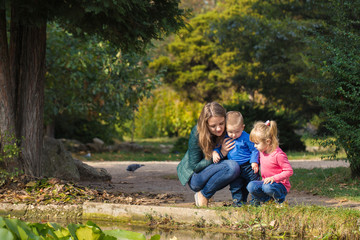 Fototapeta premium mother plays with her daughter and son in the park by the pond