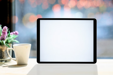 Mockup blank screen tablet with white mug on white wooden table..