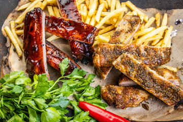barbecue grilled pork ribs on parchment with French fries and hot pepper.
