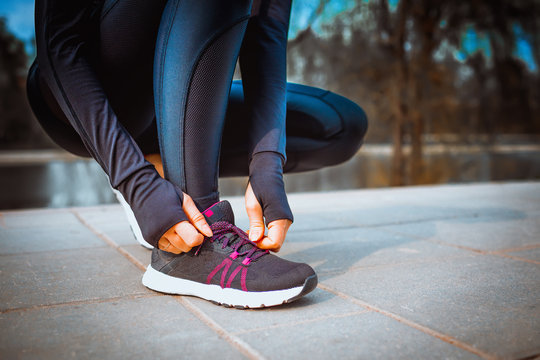 girl in running marathon stopped to lacing her shoelaces on her sneakers - sport training workout health concept