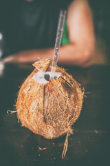 Fresh cracked coconut water drink with straw at restaurant. Local food polynesian beverage.