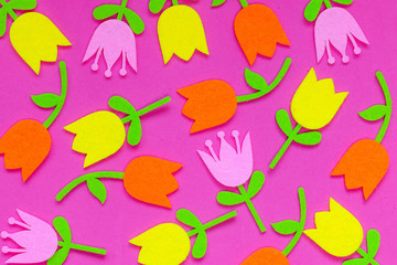 Fototapeta na wymiar Abstract floral background of felt Easter tulip flowers of pink, purple and yellow on a plain background