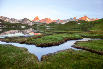 Wetland with winding brooks at Lacs de Fenetre with reflection at sunrise and Grand Jorasses; Val...