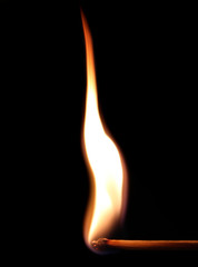 Burning match against black background in close up