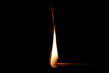 Burning match against black background in close up