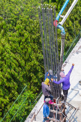 Worker pouring cement pouring into foundations and pillars formwork at building area in construction site.
