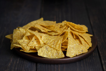 The most famous Mexican snack, nachos made con corn tortilla chips or totopos on wooden background.