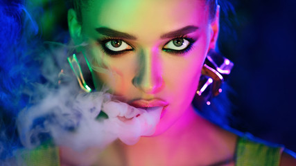 Fashion girl smoking e-cigarette in neon lights