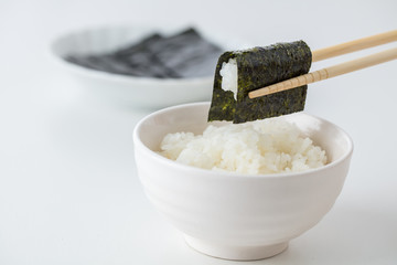 白背景に白いご飯に海苔を巻いて食べる日本人お米日本食