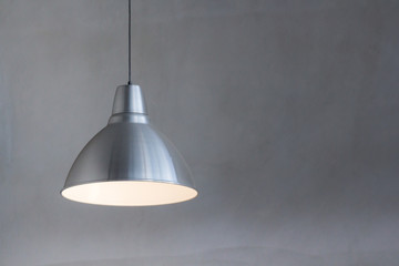 silver metal lamp hanging from ceiling with concrete wall background