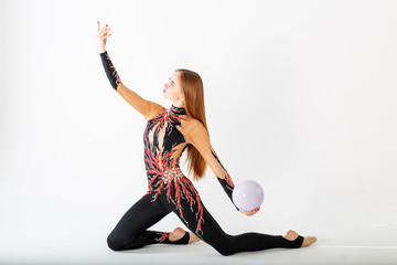 Rhythmic gymnastics. Young gymnast girl with ball on white background