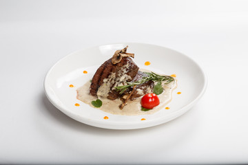 Food on white plate. Meat. Rosemary greens. A tomato. Mushrooms.