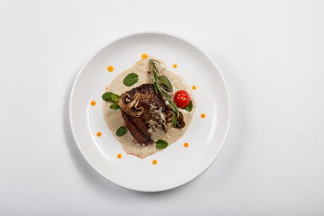 Food on white plate. Meat. Rosemary greens. A tomato. Mushrooms.