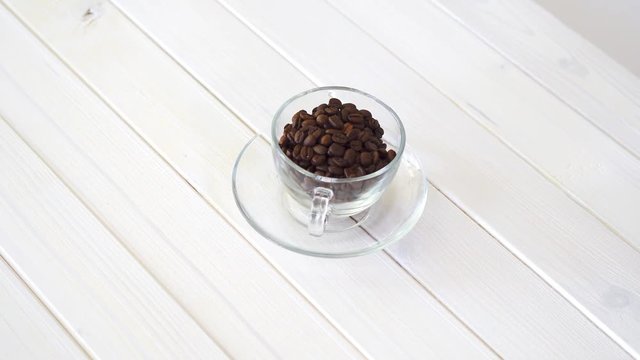 Glass cup with coffe beans on white table