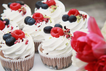Homemade pavlovas cupcakes with berries and tulips