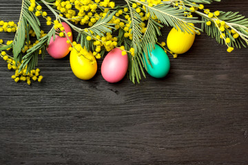 Easter background with mimosa, eggs and wooden surface