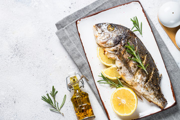 Baked dorado fish with lemon and rosemary top view.