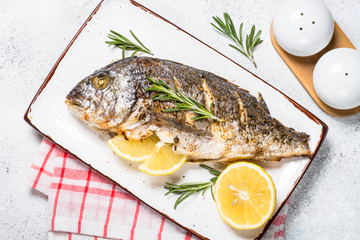 Baked dorado fish with lemon and rosemary top view.