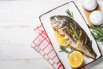 Baked dorado fish with lemon and rosemary top view.