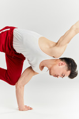 Asian male dressed in white undershirt and red sportive pants preparing to break dance contest,...