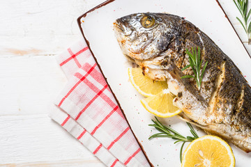 Baked dorado fish with lemon and rosemary top view.