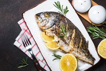 Baked dorado fish with lemon and rosemary top view.