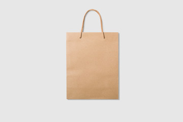 Mockup of a blank kraft paper shopping bag with handles on light grey background. High resolution.
