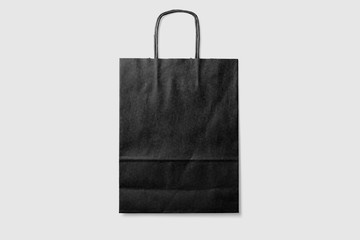 Mockup of a blank black paper shopping bag with handles on light grey background. High resolution.