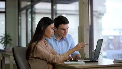 Female and male co-workers reading email laptop, planning strategy, discussion