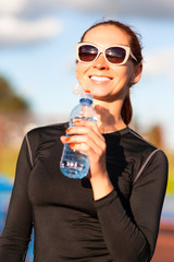 Portrait of Smiling Fitness Caucasian Woman in Sportwear and Sunglasses With Water from Bottle Outdoors